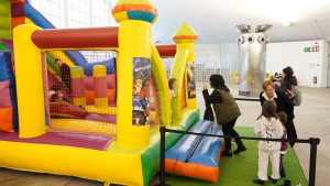 Ana Nosti habla con una niña frente a un hinchable en Comadres 2026